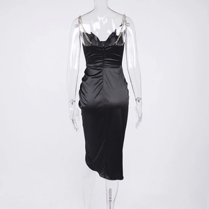 Detail of elegant black satin midi dress featuring golden metal chain straps and backless cut