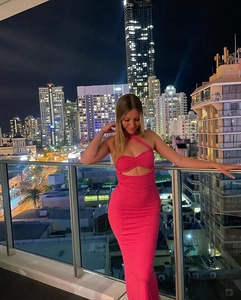 Détail de la robe longue rose vif à licou avec découpe et fronces dans un décor urbain nocturne