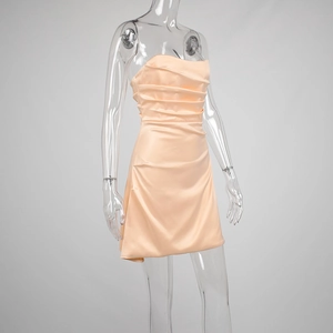 Detail of ruched satin mini dress showing pleated texture and glossy apricot fabric