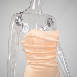 Detail of light apricot satin dress showing bust ruching and gathered fabric texture