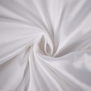 Gros plan sur un tissu en satin blanc montrant une texture lisse et des reflets soyeux