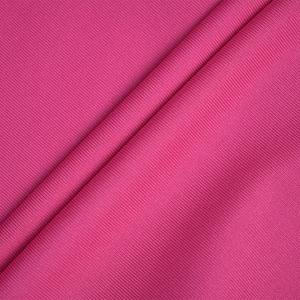 Gros plan sur un tissu en maille côtelée rose foncé avec texture et drapé naturel