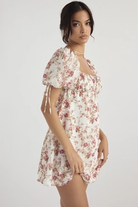Detail of pink floral print on white summer dress with puff sleeves and tie cuffs