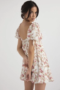 Close-up of backless floral mini dress with puff sleeves and delicate pink rose patterns