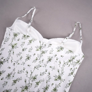 Détail des bretelles réglables et imprimé floral vert sur une robe d'été blanche
