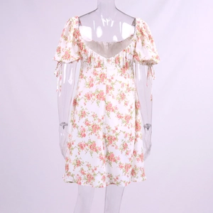 Back view of a floral mini dress with puff sleeves and tie details on a mannequin
