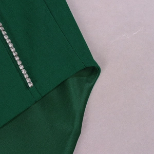 Détail d'un haut corset vert foncé avec bordure en strass argentés et texture tissée chic