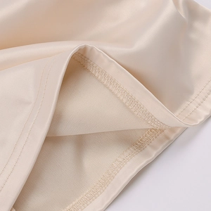 Detailaufnahme von Saum und Overlock-Nähten des champagnerfarbenen Satinkleides aus nächster Nähe