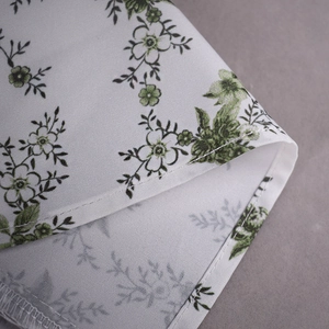 Gros plan sur l'imprimé floral vert sur tissu en coton blanc avec détails de couture précis