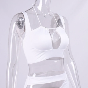Dettaglio del crop top bianco con scollo all'americana e spalline sottili su manichino