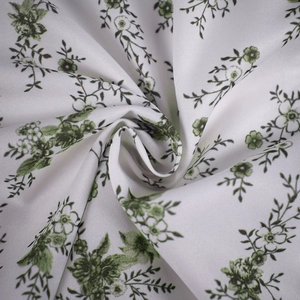 Gros plan sur le tissu à fleurs vertes d'une robe d'été blanche à texture sergée