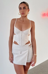 Detail of white two-piece set with corset top and asymmetrical mini skirt featuring buckles