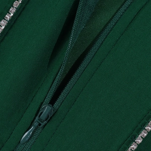 Détail macro du tissu vert foncé avec fermeture éclair invisible et strass blancs brillants