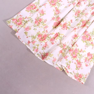 Detail of floral chiffon mini dress showing pink rose pattern on white fabric