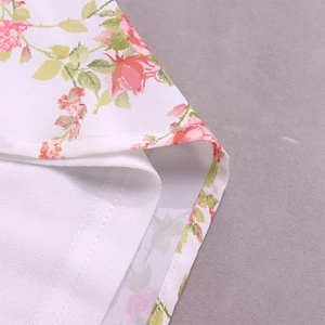 Detailed close-up of floral print fabric and neat stitching on a white summer mini dress