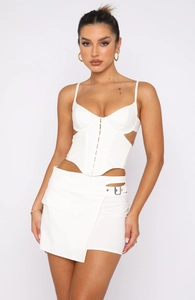 Detailed close-up of white corset top with side cut-outs and metal buckle skirt detail