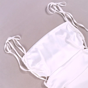 Detailed close-up of white satin dress showing thin spaghetti straps and silky texture