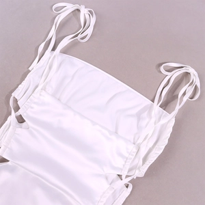 Detail shot of white satin slip dress featuring elegant ribbon tie shoulder straps