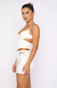 Detail of white two-piece crop top and skirt with metal buckle and cutout side design