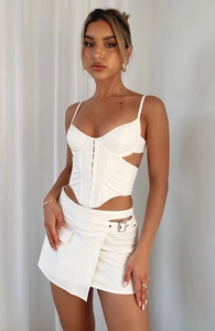 Detail of white corset top with boning design and hollow-out skirt with metal buckles