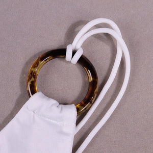 Detail eines weißen Strickkleides mit Schildpatt-Harzring und dünnen Neckholder-Trägern