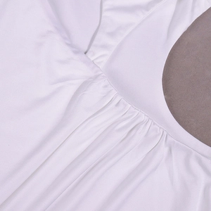 Detailaufnahme des weißen Kleides mit eleganten Raffungen und glatter Stoffstruktur