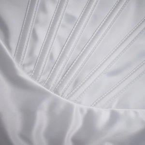 Macro shot of white satin dress featuring intricate radial stitching and silky texture