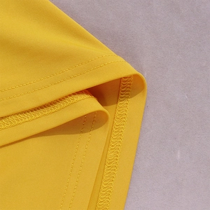 Detailed close-up of double-stitched hem and overlock stitching on yellow dress fabric