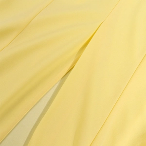 Detailed macro view of the bright yellow fabric and fine slit seam of the long dress