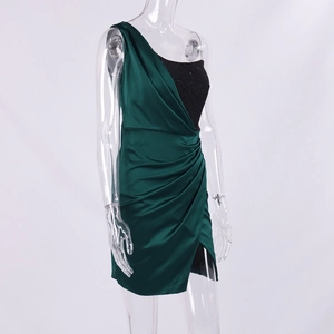Détail du haut à sequins asymétrique et jupe en satin vert à plis sur mini robe