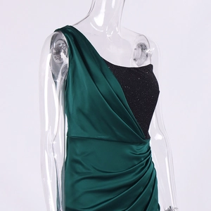 Détail de la robe en satin vert émeraude avec épaule asymétrique et sequins brillants