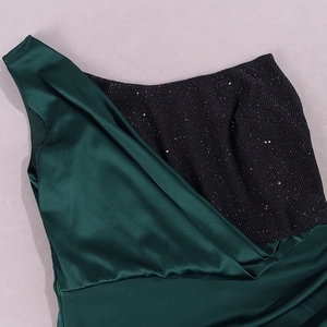 Détails du tissu noir à paillettes et du satin vert émeraude sur la robe asymétrique