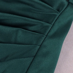 Gros plan sur le tissu en satin plissé vert émeraude avec un lustre subtil pour robe