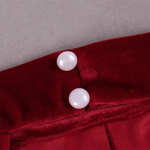 Détail du tissu en velours rouge foncé avec boutons perles blancs et coutures fines