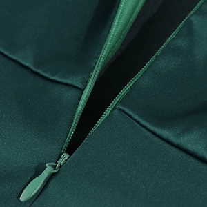 Détail d'une fermeture éclair invisible sur une robe en satin vert foncé en tissu lisse