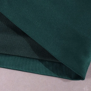 Détail de robe satin vert foncé montrant la soie lisse et la doublure en maille noire