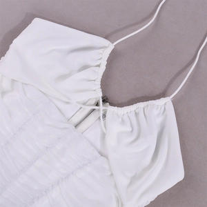 Detail of white ruched halter neck top with metal zipper and fine straps on light fabric