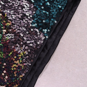 Détail macro de paillettes colorées sur robe moulante noire à manches longues Noël