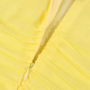 Detail of yellow mesh fabric with a matching invisible zipper and fine pleated texture