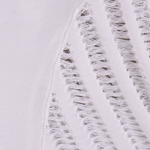Dettaglio del tessuto a maglia bianco con particolari traforati ed effetti sfrangiati