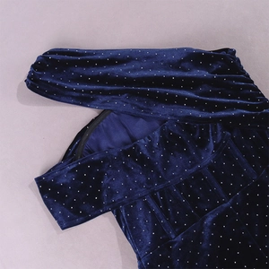 Détail du tissu en velours bleu foncé avec des strass argentés brillants et texture