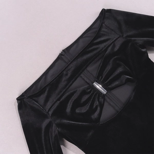Detalle de vestido de terciopelo negro con corte de hombros caídos y barras metálicas