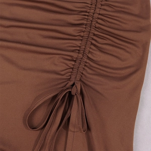 Close-up of brown ruched fabric detailing with adjustable drawstrings and a tied bow