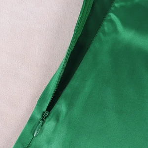 Detailed view of the invisible zipper on a green satin evening dress fabric
