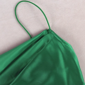 Detail of emerald green satin dress featuring sleek spaghetti straps and silky texture