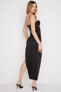 Detail of high side slit and pleated satin fabric on a backless black midi evening dress