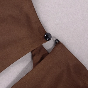 Dettaglio di un abito marrone scuro con fine tessuto twill e chiusura con bottone nero