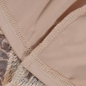 Détail de couture surjet pro et dentelle à paillettes dorées sur la robe de couleur beige