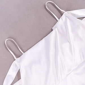 Detail of white satin dress featuring thin straps and elegant draped neckline texture