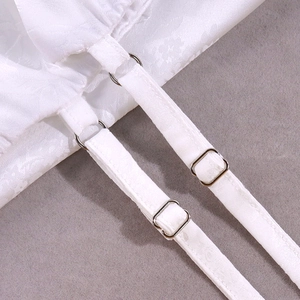 Dettaglio delle fibbie regolabili e della trama jacquard floreale su abito in raso bianco